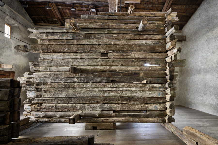 Exhibition view, Augustas Serapinas, Remains of the House from Skirgiškės, 2022, reclaimed wood, 370 x 480 x 500 cm. Photo: Ralph Feiner, Courtesy of the artist and Galerie Tschudi