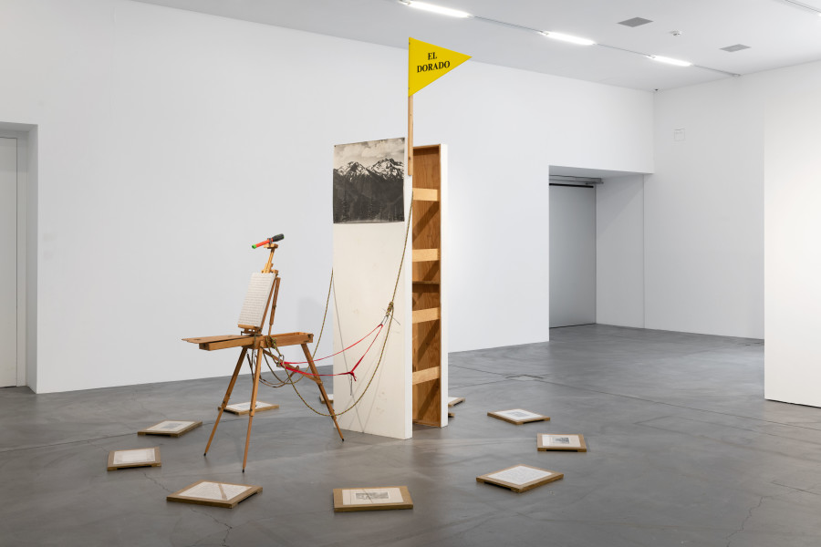 Renée Green, Idyll Pursuits, 1991, Installation. Mixed media: wooden structure, three plaques with rubber-stamped text, three prize ribbons, photographic print, mud footprints, acrylic sign [El Dorado], portable easel, kaleidoscope, palette with rubber-stamped text, canvas with rubber- stamped text, climbing rope, eleven wooden plaques with rubber-stamped text and image reproductions, engraved brass plate. Courtesy Kunststiftung Ingvild und Stephan Goetz. Photo: Flavio Karrer.