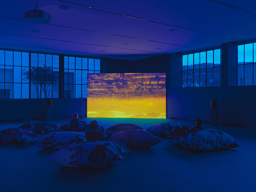 Korakrit Arunanondchai & Alex Gvojic, Songs for living, 2021, Single-channel video, bleached denim pillows, blue photographic gel, blue carpet, Sammlung Migros Museum für Gegenwartskunst, photo: Stefan Altenbruger